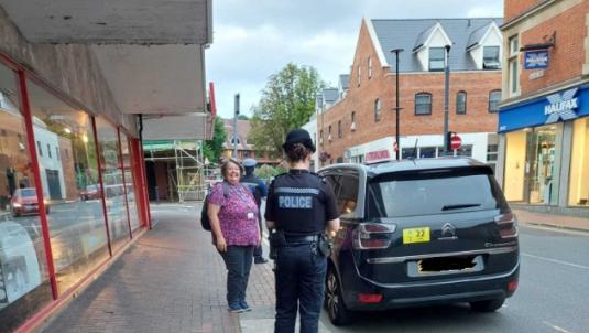 Police officer and council licensing officer with taxi in high street