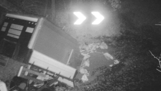 Black and white CCTV image of truckload of waste being tipped onto ground