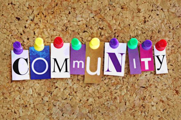 Corkboard with the letters spelling 'Community' in different colours and fonts arranged with coloured pins holding them in place 