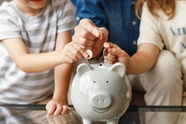grey piggy bank and three family members adding coins