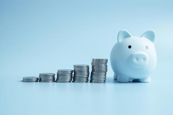 blue piggy bank with coins stacked up next to it