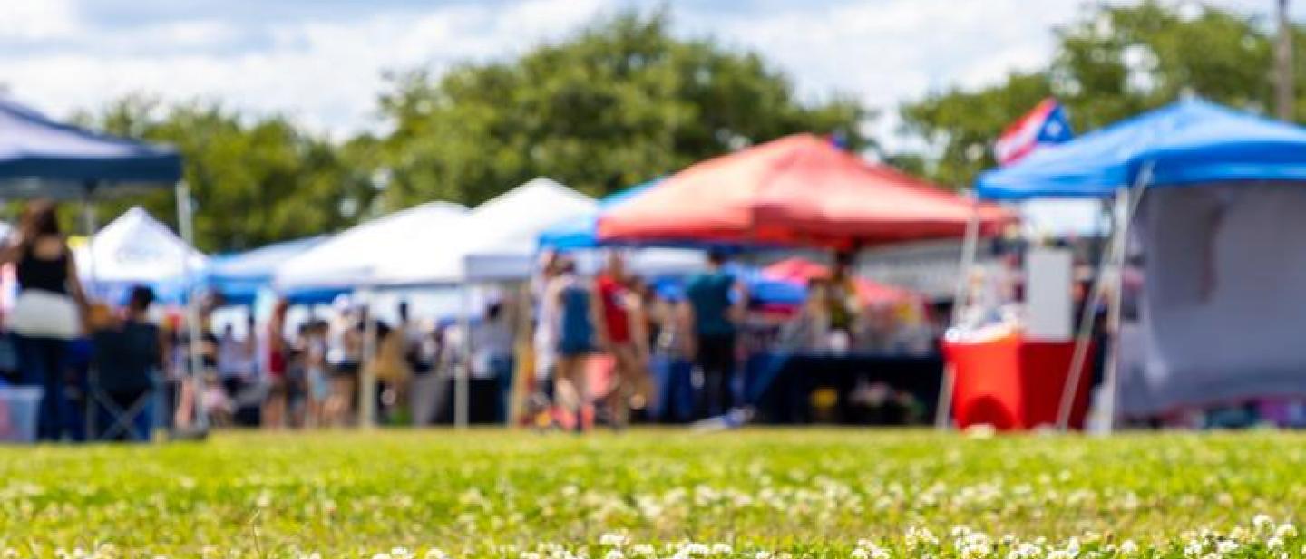 Stalls at a fete taking place in a sunny field