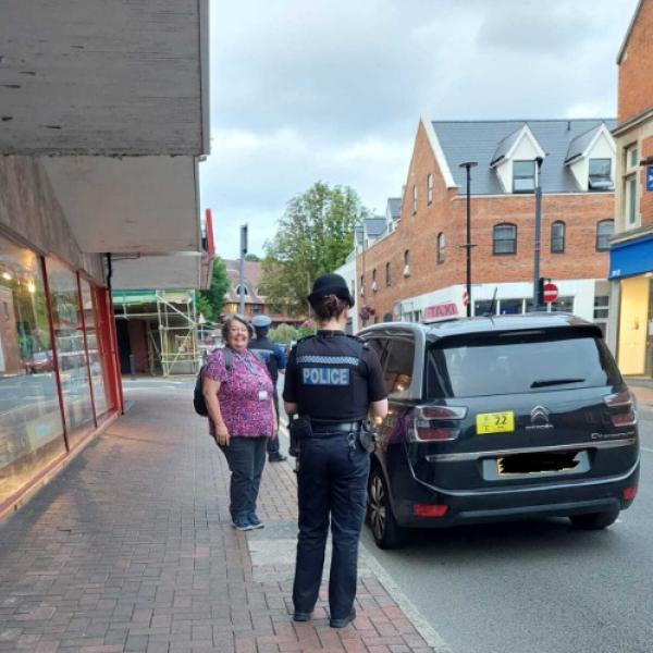 Police officer and council licensing officer with taxi in high street