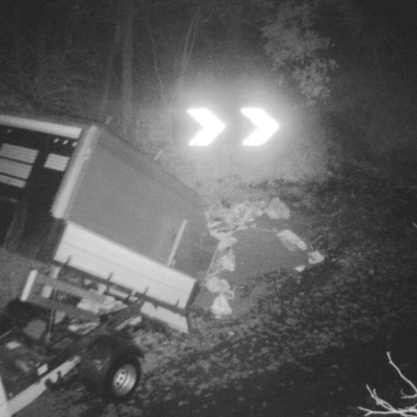 Black and white CCTV image of truckload of waste being tipped onto ground