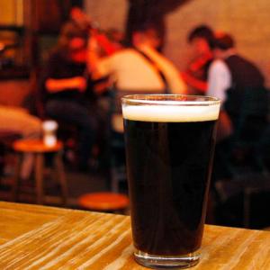A pint of stout with musician playing in the background