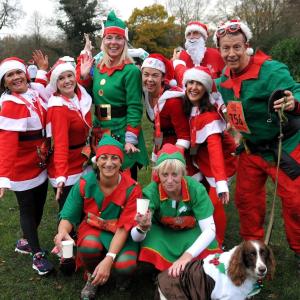 group of people and a dog dressed in festive Santa and elves costume at a previous Jingle Jog