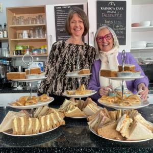 Two women behind the counter at The Rainbow Cafe with afternoon tea